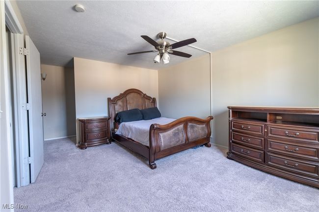 Bedroom with a ceiling fan, baseboards, a textured ceiling, and light colored carpet | Image 17