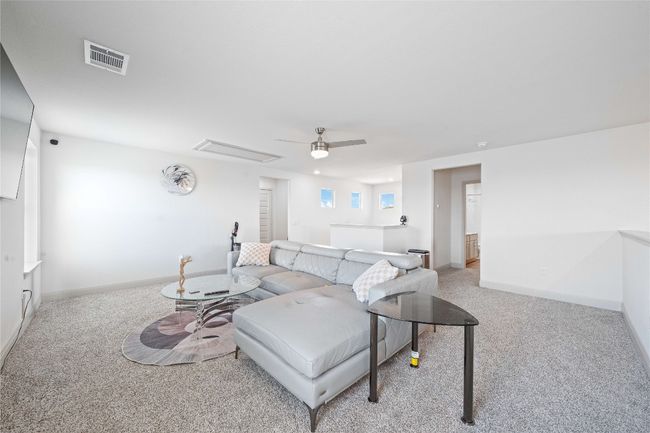 Carpeted living area with ceiling fan, baseboards, and visible vents | Image 19