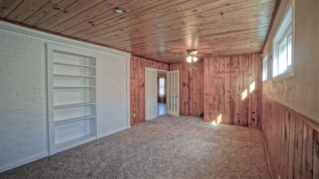 Unfurnished bedroom featuring multiple windows, wooden ceiling, carpet flooring, and wood walls | Image 10