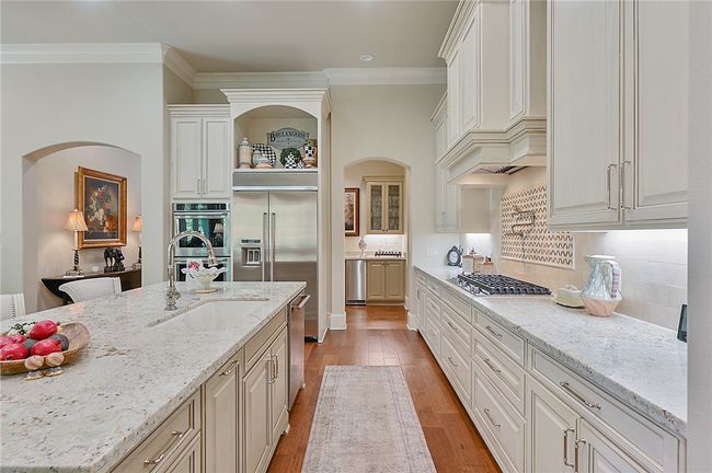 Kitchen with open shelves, stainless steel appliances, a sink, light wood-type flooring, and light stone countertops | Image 19