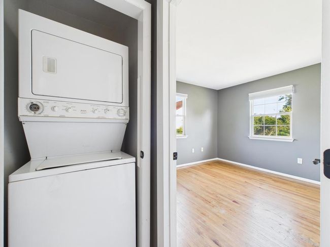 Washroom with estacked washer and dryer and wood finished floors | Image 27