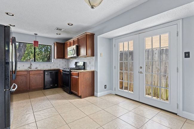 French doors right beside the kitchen open to the backyard, giving the space a bright and open feel while inviting in fresh air or easy access to al fresco meals | Image 10