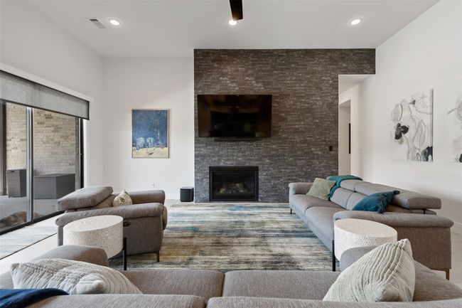 Living room with a stone fireplace, recessed lighting, and visible vents | Image 16