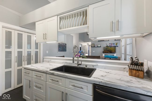 kitchen with stainless steel dishwasher, white cabinetry, and light stone counters | Image 11