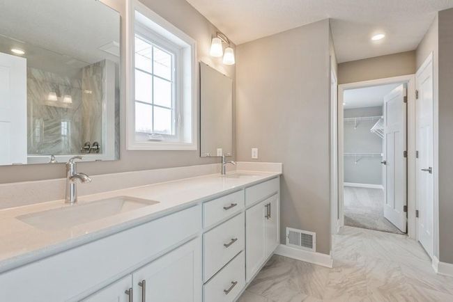 (Photo is of an inventory home, actual homes finishes will vary) An extension of the primary suite, this private and spa-like bath contains a double-vanity, a walk in shower with 2 shower heads and 2nd walk-in closet. | Image 14