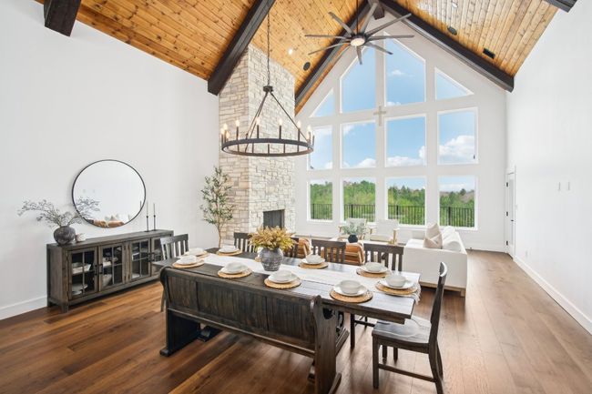 Dining room featuring high vaulted ceiling, ceiling fan, hardwood / wood-style flooring, a wood ceiling with exposed beams, and a fireplace | Image 10