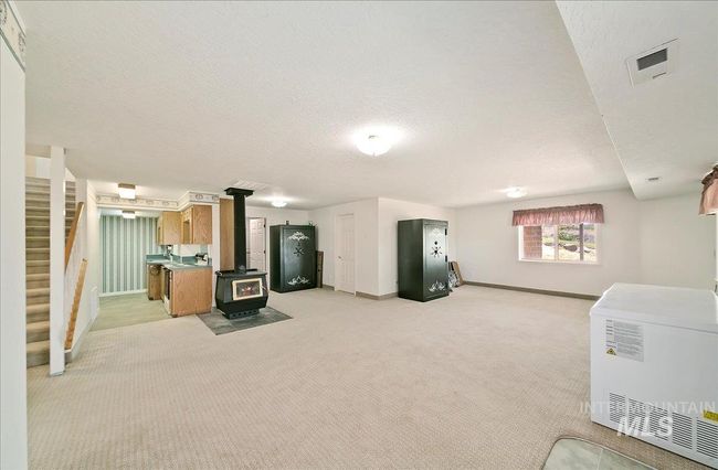 Living room featuring a wood stove, stairs, light carpet, and a textured ceiling | Image 25