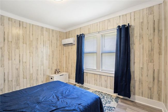 Bedroom with a wall mounted air conditioner, wood walls, multiple windows, and baseboards | Image 11