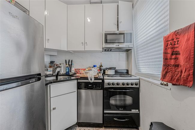 Kitchen with appliances with stainless steel finishes, white cabinetry, backsplash, and dark countertops | Image 15