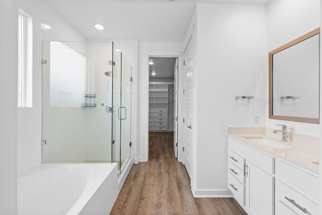 Bathroom featuring vanity, a walk in closet, a bath, a shower stall, and wood finished floors | Image 14