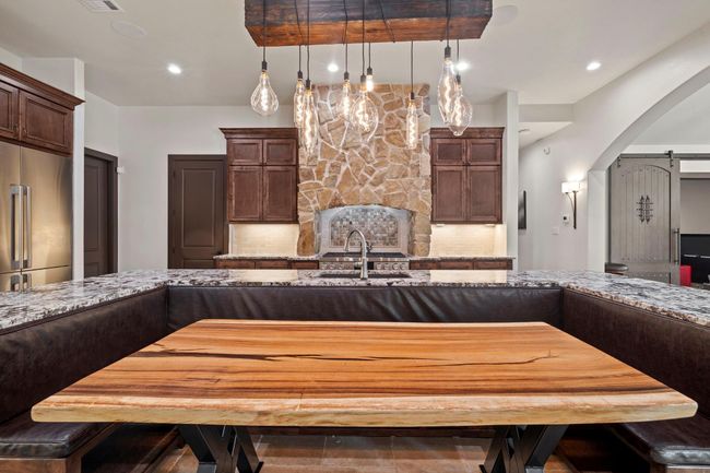 Built in island seating accenting stonework with large gas cooktop. | Image 17