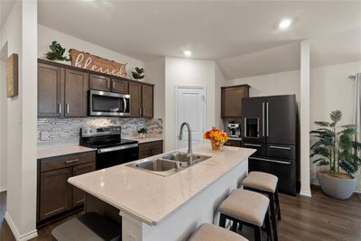 Kitchen with dark hardwood / wood-style flooring, stainless steel appliances, dark brown cabinetry, a kitchen island with sink, and sink | Image 3