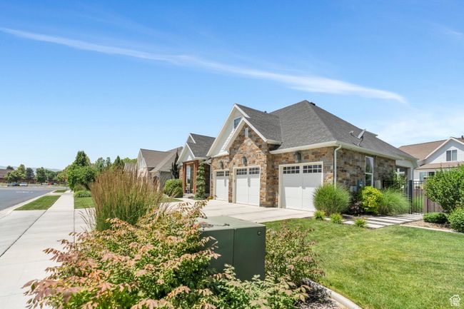 View of front facade featuring an attached garage, stone siding, concrete driveway, and roof with shingles | Image 80