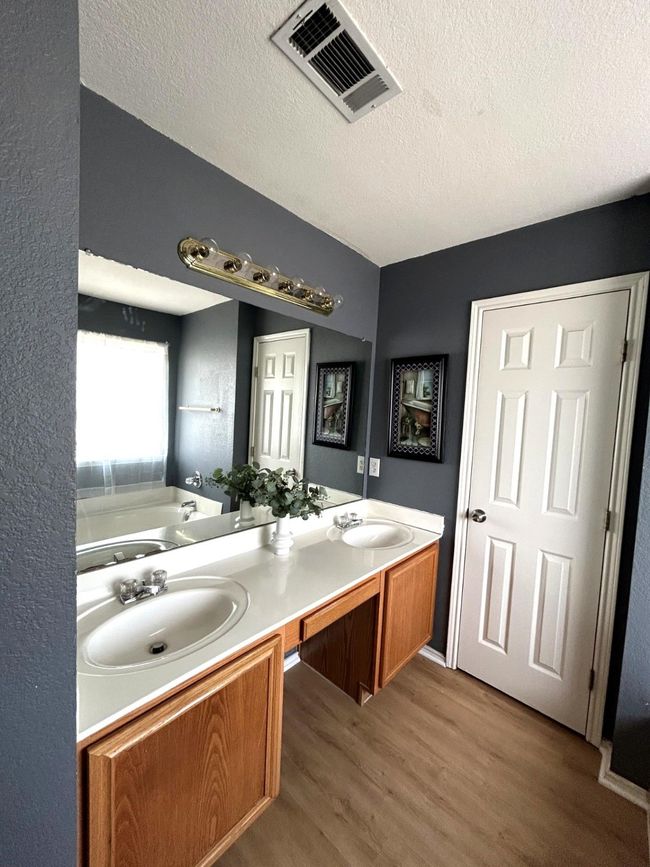 Bathroom featuring wood finished floors, double vanity, a bath, and a textured ceiling | Image 10