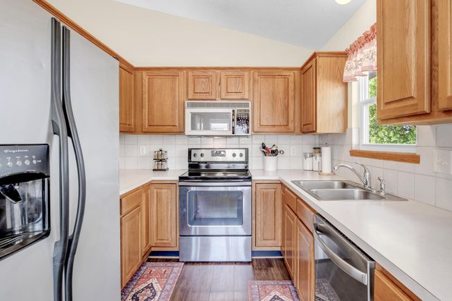 Kitchen with stainless steel appliances, a sink, lofted ceiling, light countertops, and decorative backsplash | Image 11