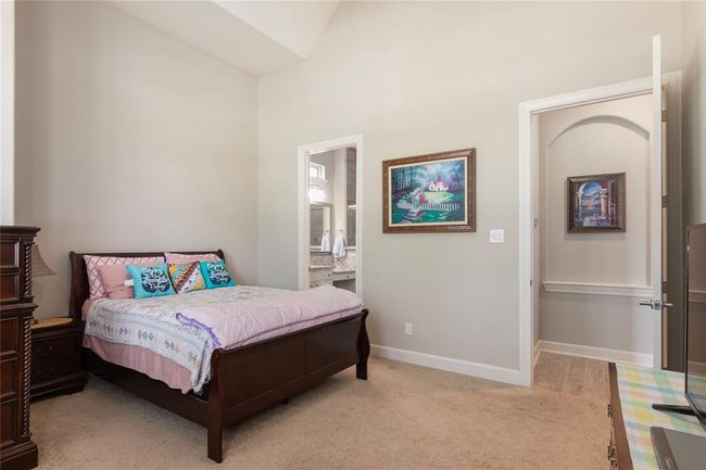 Cozy bedroom with a plush carpet and neutral wall colors is the perfect space for extended guest stays. An en-suite bathroom is visible, enhancing convenience. | Image 7