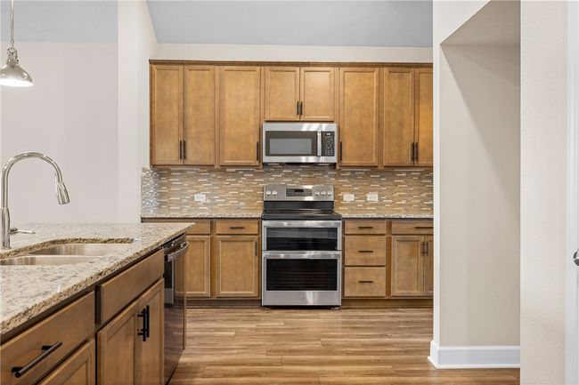 Kitchen with appliances with stainless steel finishes, a sink, light wood-type flooring, and brown cabinetry | Image 17