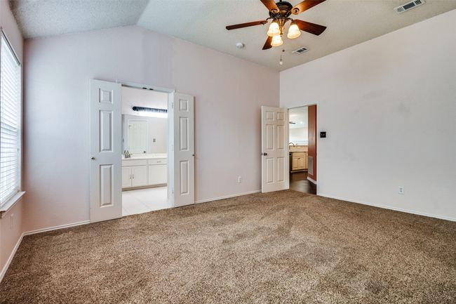 Unfurnished bedroom with vaulted ceiling, light carpet, ensuite bath, a textured ceiling, and ceiling fan | Image 21