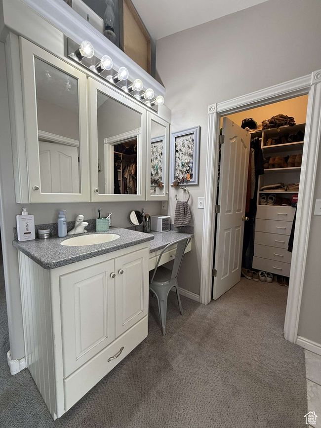 Bathroom featuring vanity, baseboards, a spacious closet, and carpet | Image 32