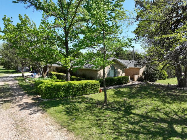 View of side of property featuring a lawn, roof with shingles, and brick siding | Image 30