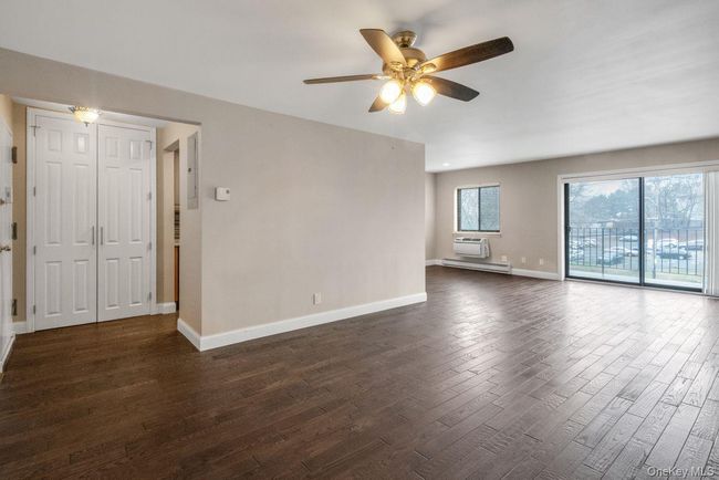 Spare room with a wall mounted air conditioner, dark wood-style floors, baseboards, and a ceiling fan | Image 5