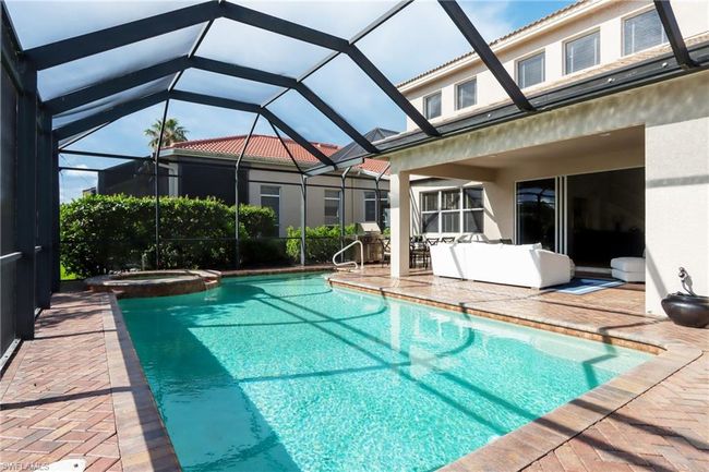 View of pool featuring a patio area, a pool with connected hot tub, grilling area, and glass enclosure | Image 25