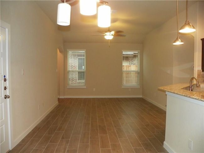 Unfurnished living room with a sink, a ceiling fan, baseboards, and dark wood-type flooring | Image 4