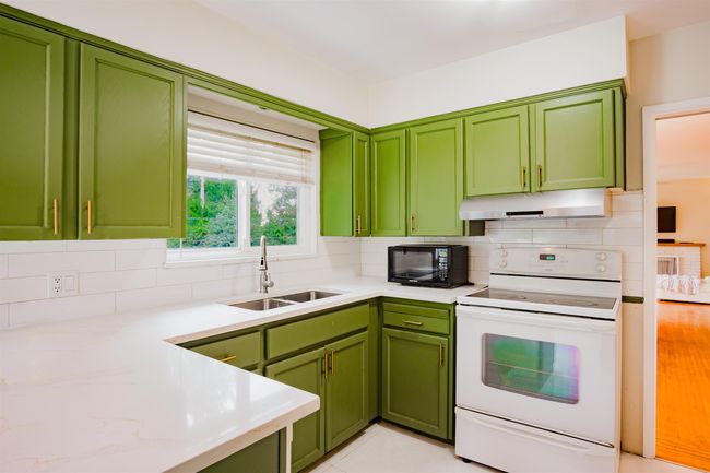 Kitchen featuring a sink, black microwave, green cabinets, under cabinet range hood, and white electric stove | Image 11
