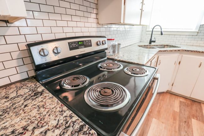 Kitchen featuring a sink, white cabinetry, light wood-style floors, decorative backsplash, and stainless steel range with electric stovetop | Image 11