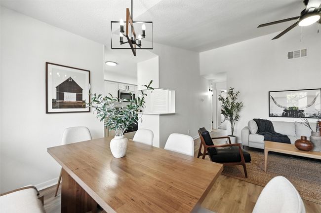 Dining space featuring wood finished floors, a ceiling fan, and a chandelier | Image 12