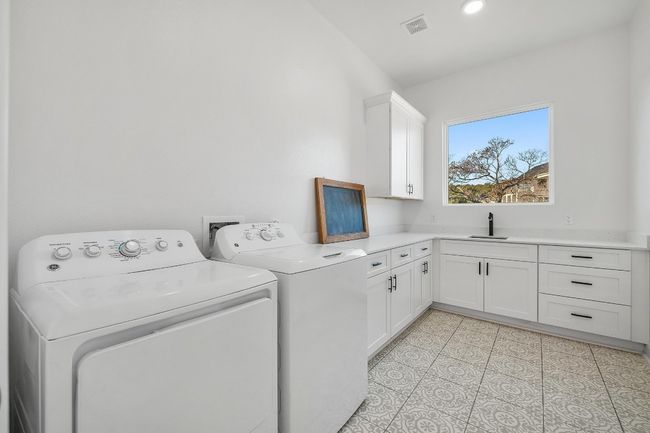 The conveniently located main-level laundry room is designed for efficiency and style, featuring a built-in sink, ample storage, and counter space for folding. Equipped with modern appliances, this well-appointed space ensures seamless functionality for everyday chores. | Image 31
