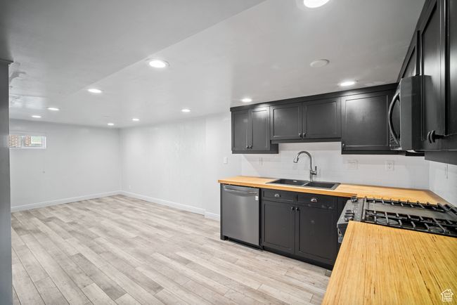 Kitchen with wooden counters, a sink, dishwasher, backsplash, and recessed lighting | Image 16