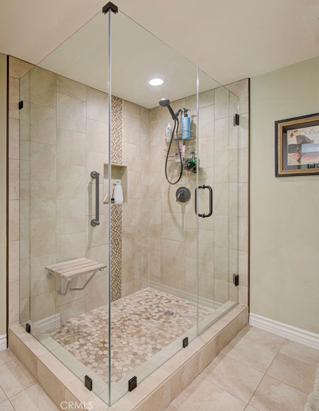 Oversized shower in primary bathroom has a seat, grab bar and convenient accessory shelf. | Image 23