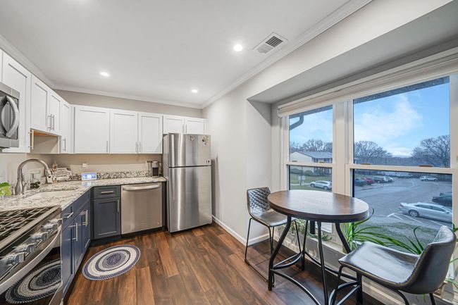 Kitchen featuring a sink, stainless steel appliances, visible vents, white cabinets, and ornamental molding | Image 15