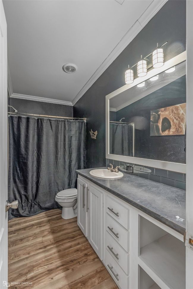 Full bathroom featuring a shower with curtain, vanity, toilet, ornamental molding, and wood finished floors | Image 33