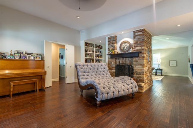 Living area with a brick fireplace, wood finished floors, built in features, baseboards, and recessed lighting | Image 5