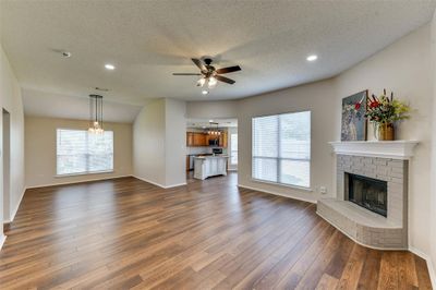 Unfurnished living room with a brick fireplace, hardwood / wood-style flooring, and a healthy amount of sunlight | Image 2