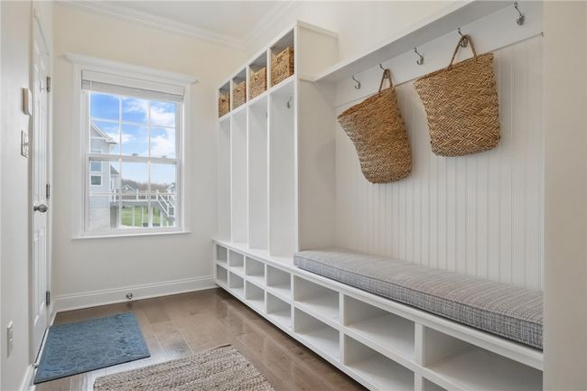Bright and functional mudroom featuring built-in cubbies, bench seating, and wall hooks for effortless organization. A large window fills the space with natural light, complementing the clean white finishes and warm wood flooring. Door leads directly to the attached two-car garage. | Image 8