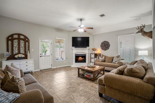 Natural light pours through the windows, gleaming off the tile floors as you step into the living room. A corner fireplace anchors the space with warmth and character. | Image 14