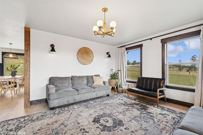 Living area featuring wood finished floors, a notable chandelier, and baseboards | Image 9