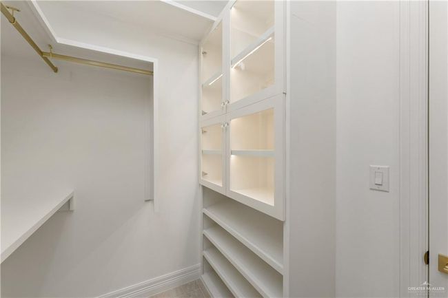 Spacious Primary ClosetThoughtfully designed closet with ample storage, custom drawers, open shelving, and dual hanging spaces with brass rods. | Image 22