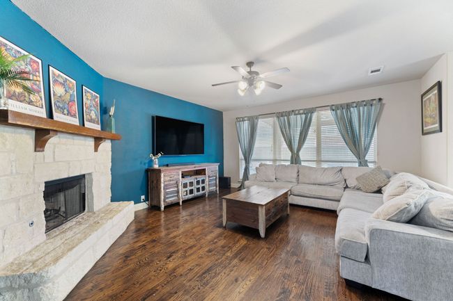 Living room featuring visible vents, baseboards, ceiling fan, wood finished floors, and arched walkways | Image 9