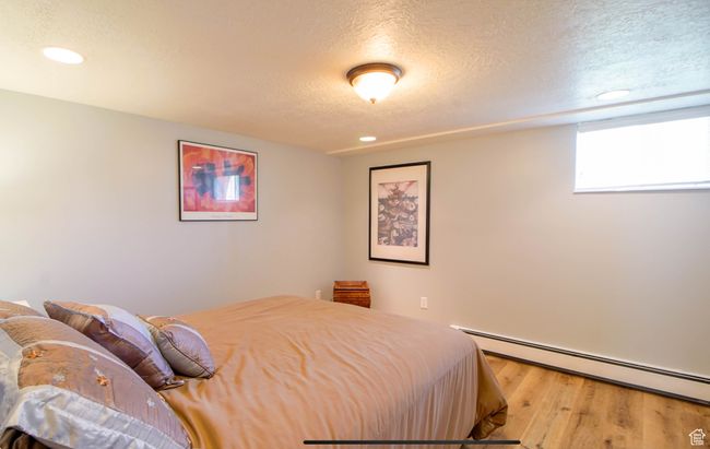 Bedroom featuring baseboard heating, a textured ceiling, wood finished floors, and recessed lighting | Image 15
