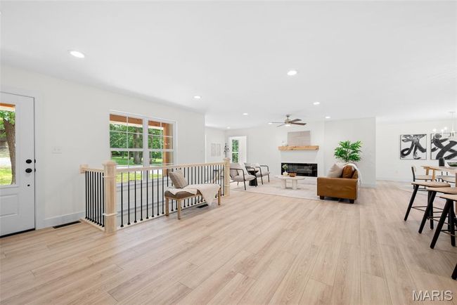 Living room featuring light wood-style floors, recessed lighting, a glass covered fireplace, a chandelier, and ceiling fan | Image 5