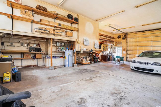 Garage featuring water heater and a workshop area | Image 31