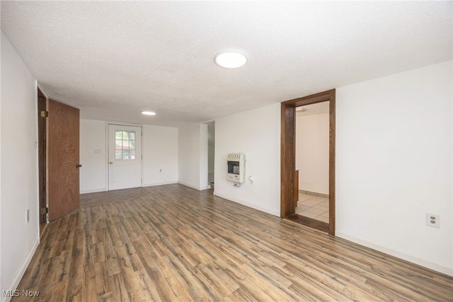 Living room with wood finished floors, heating unit, a textured ceiling, and baseboards | Image 9