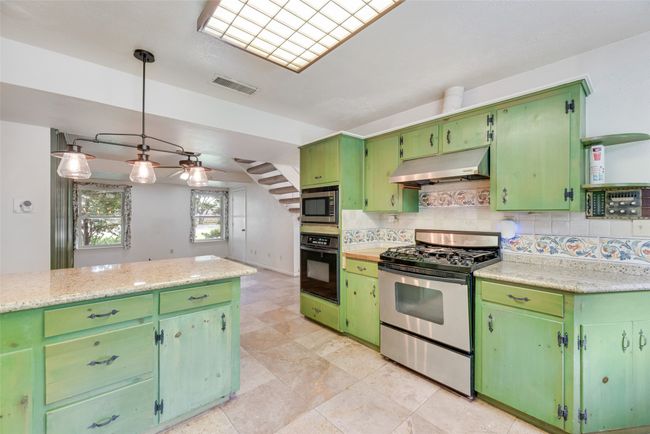 Kitchen with appliances with stainless steel finishes, under cabinet range hood, light countertops, and backsplash | Image 14