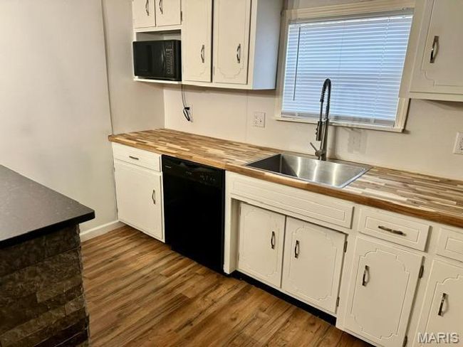 Kitchen with sink, white cabinets, black appliances, and wooden counters | Image 20