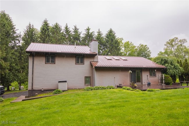 Back of property with a yard, metal roof, a patio, and a chimney | Image 23