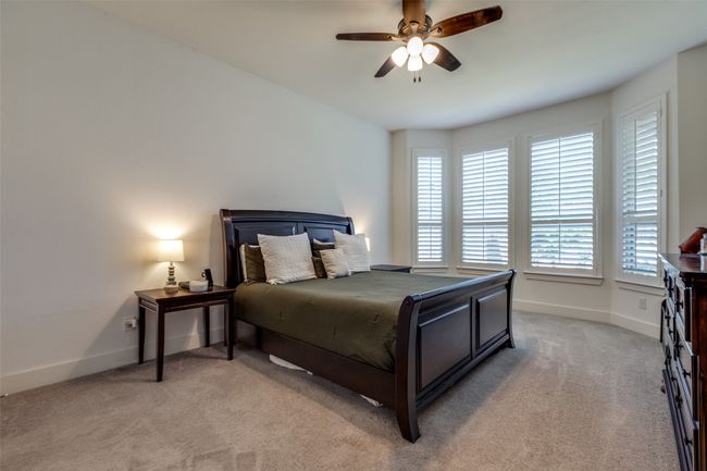 Bedroom featuring light carpet, baseboards, and multiple windows | Image 23